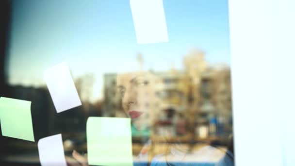 Geschäftsfrau betrachtet klebrige Zettel auf Glasplatte — Stockvideo