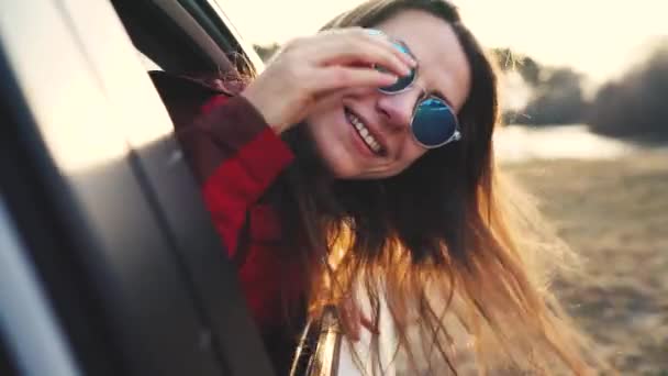 幸せな若い女性の車の助手席に座っていると、晴れた日に窓の外見て — ストック動画