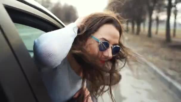 Glad ung kvinna sitter i passagerarsätet i bilen och tittar ut fönstret solig dag — Stockvideo