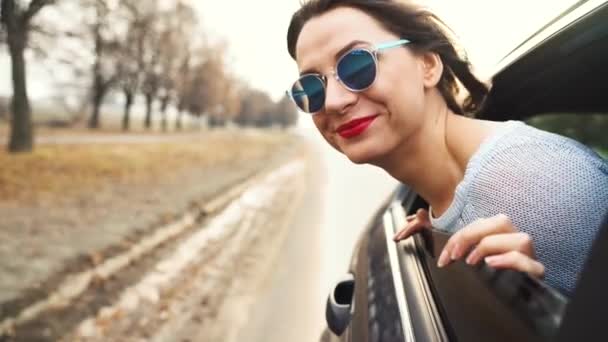 Wanita muda yang bahagia duduk di kursi penumpang mobil dan melihat keluar jendela pada hari yang cerah — Stok Video