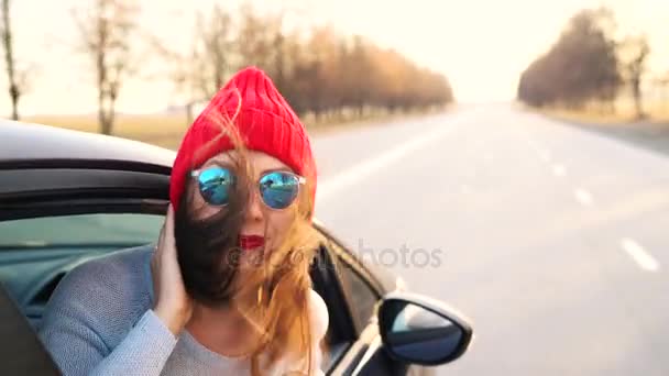 Gelukkig jonge vrouw in auto passagiersstoel zitten en kijkt uit raam op een zonnige dag — Stockvideo