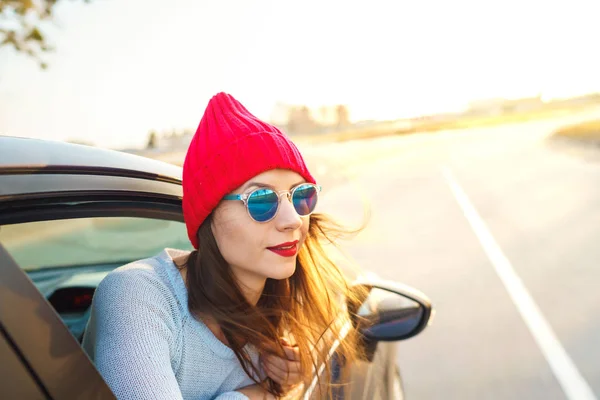 Jovem feliz sentada no banco do passageiro do carro e olhando para fora — Fotografia de Stock