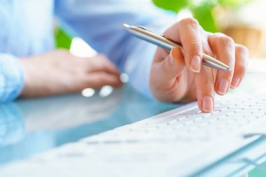 Kadın ofis çalışanı ile kalem el klavyede yazarak