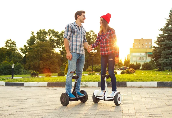 Young couple riding hoverboard - electrical scooter, personal ec