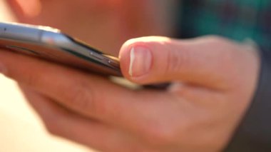 Kadın bir akıllı telefon açık havada günbatımında kullanıyor