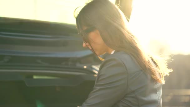 Улыбающаяся белая женщина достает из машины свои сумки для покупок — стоковое видео
