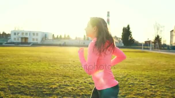 La mujer corre por el estadio al atardecer — Vídeo de stock