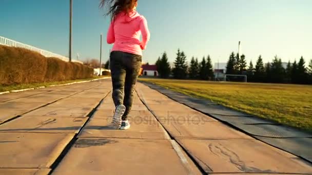 Mulher corre pelo estádio ao pôr-do-sol — Vídeo de Stock