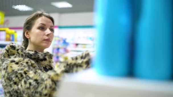 Mujer está de compras en la tienda de productos químicos domésticos y cosméticos — Vídeos de Stock