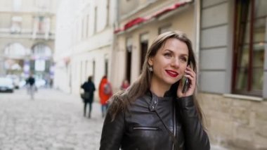 Kadın kırmızı ile smartphone üzerinde konuşurken dudakları ve Ortaçağ cadde boyunca elini kolunu sallaya dönüyor