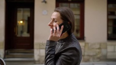 Kadın kırmızı ile smartphone üzerinde konuşurken dudakları ve Ortaçağ cadde boyunca elini kolunu sallaya dönüyor
