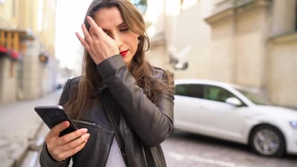 Kadın kırmızı dudaklar ile smartphone kullanır ve Ortaçağ cadde boyunca elini kolunu sallaya dönüyor — Stok video