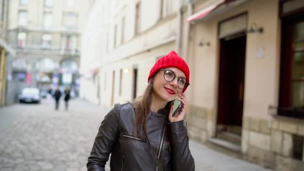 Kadın kırmızı ile smartphone üzerinde konuşurken dudakları ve Ortaçağ cadde boyunca elini kolunu sallaya dönüyor — Stok video