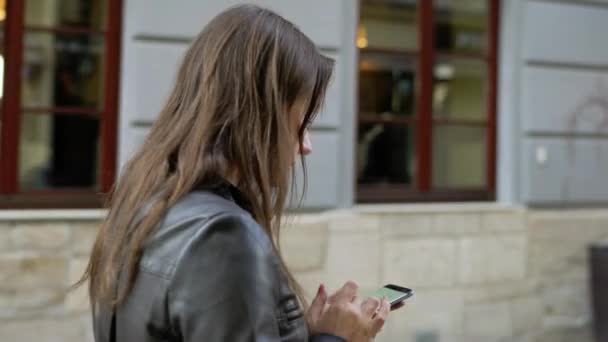 Mujer con labios rojos utiliza smartphone y paseos por la calle medieval — Vídeo de stock