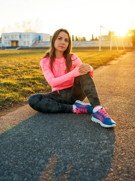 Woman is sitting in the stadium after evening running