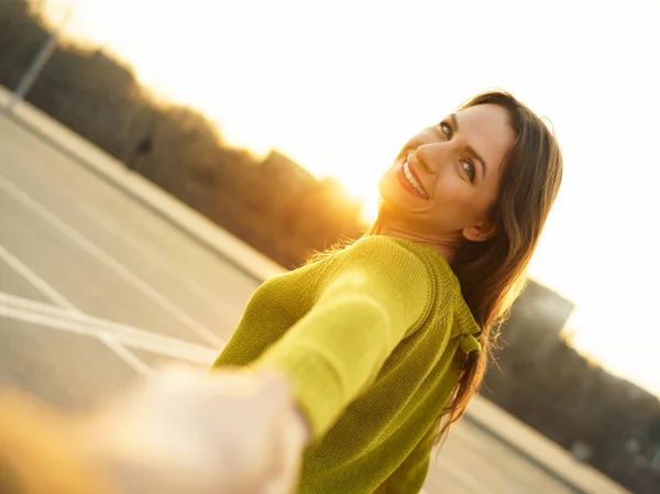 Glückliche junge Frau, die an der Hand eines Mannes zieht - Hand in Hand auf einem — Stockfoto