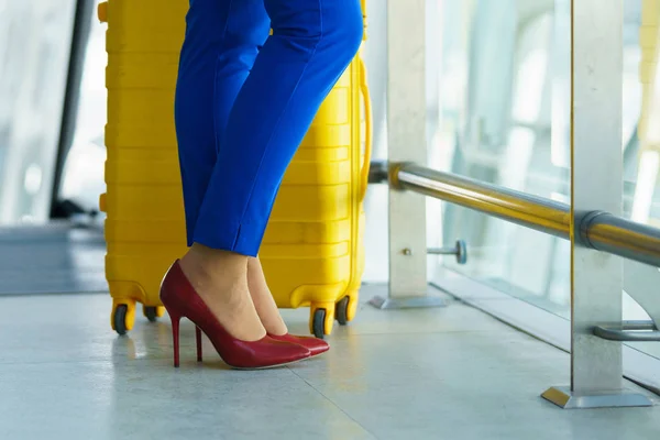 Mujer con ropa brillante y maleta amarilla en el airpo — Foto de Stock