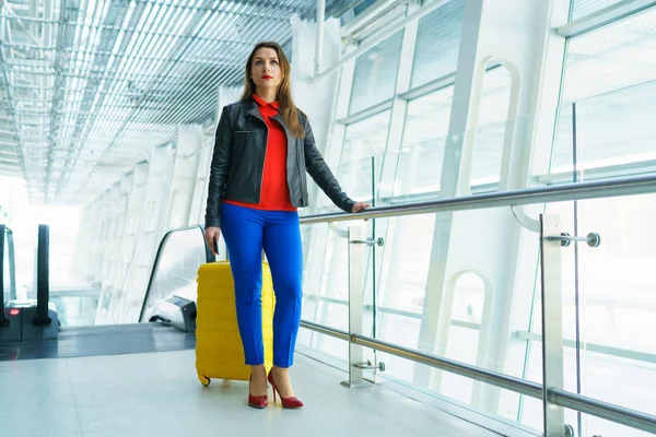 Mujer con ropa brillante y maleta amarilla en el airpo —  Fotos de Stock