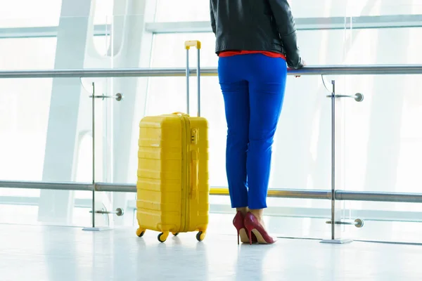 Mujer con ropa brillante y maleta amarilla en el airpo — Foto de Stock