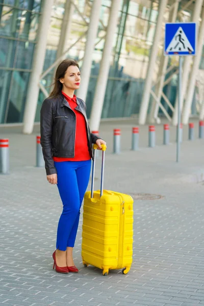 Woman in bright clothes with the yellow suitcase is standing nea — Stock Photo, Image