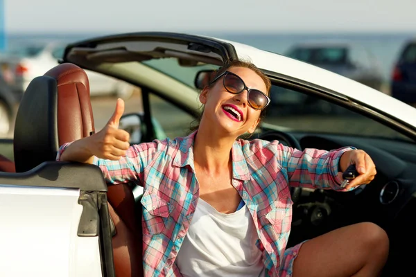 Jeune jolie femme assise dans une voiture décapotable avec les clés en — Photo