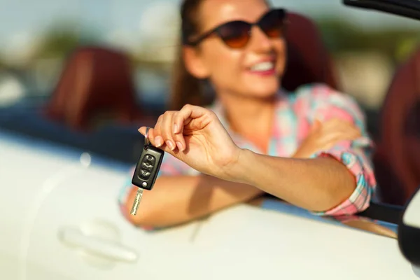 Jovem mulher bonita sentada em um carro conversível com as chaves em — Fotografia de Stock