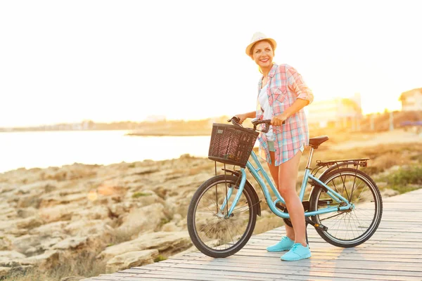 Jolie femme insouciante avec vélo chevauchant sur un chemin en bois à th — Photo