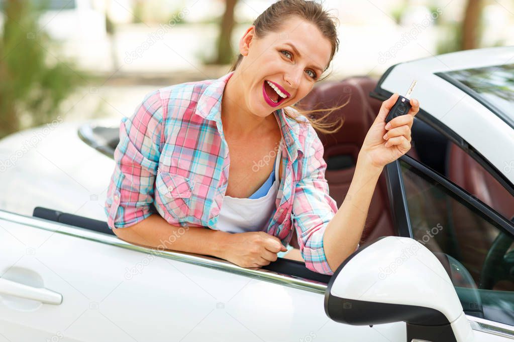 Young pretty woman is standing near the convertible car with the