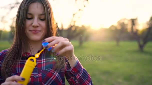 Жінка дме мильні бульбашки на відкритому повітрі — стокове відео