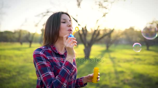 Mujer soplando burbujas de jabón al aire libre — Vídeos de Stock