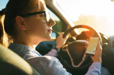 Mutlu kadın bir navigator bir smartphone içinde bir araba sürüş sırasında kullanır