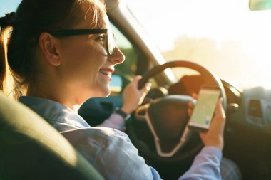Mutlu kadın bir navigator bir smartphone içinde bir araba sürüş sırasında kullanır