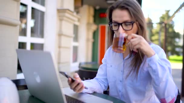 Vacker ung kvinna som arbetar i en café utomhus — Stockvideo