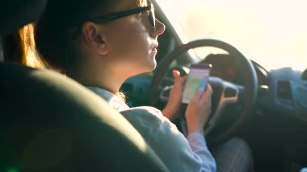 Frau mit Brille mit Smartphone im Auto — Stockvideo