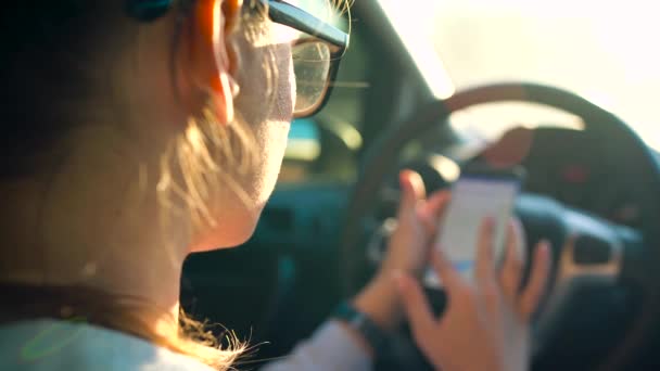 Vrouw in glazen met behulp van een smartphone in de auto — Stockvideo