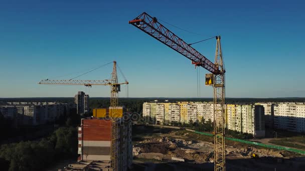 Guindastes de construção industrial e edifícios sobre o sol ao pôr do sol — Vídeo de Stock