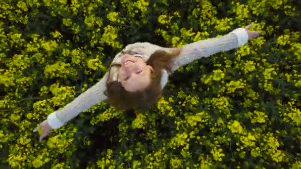 Jeune femme avec les bras tendus dans un champ de canola jaune 