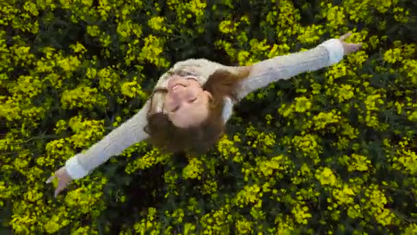 Mujer joven con los brazos extendidos en un campo de canola amarillo — Vídeos de Stock