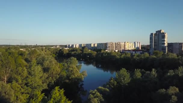 Vliegen boven de bomen en het meer in de stad bij dageraad - luchtfoto video-opnamen — Stockvideo