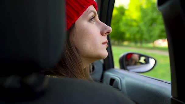 Glad ung kvinna sitter i passagerarsätet i bilen och tittar ut fönstret solig dag — Stockvideo