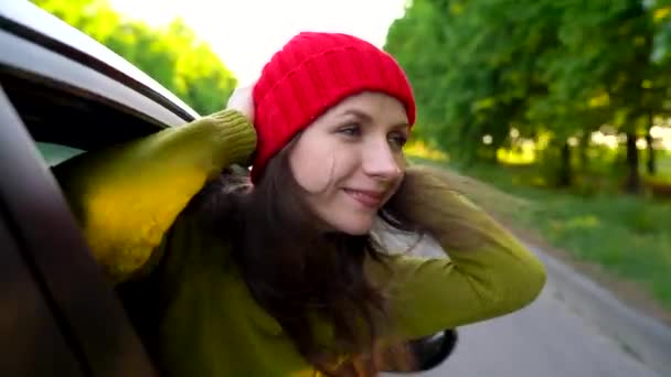 幸福的年轻女人，坐在车乘客座位上，看窗外阳光明媚的日子 — 图库视频影像