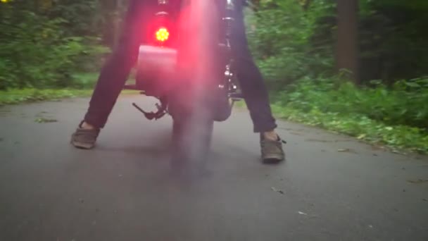 Чоловік робить вигоряння шин на мотоциклі на лісовій дорозі — стокове відео