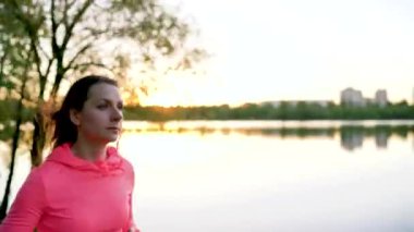 Kadın parkta göl kıyısında günbatımı çalışır