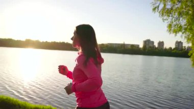 Kadın parkta göl kıyısında günbatımı çalışır