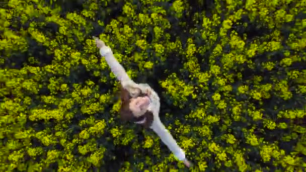 Jeune femme avec les bras tendus dans un champ de canola jaune 