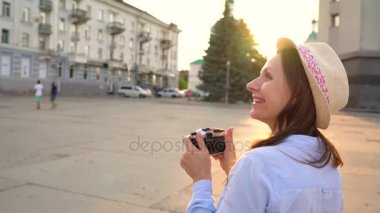 Kız şehir ve turistik fotoğraflarını alarak çevresinde bir film kamerası üzerinde yürüyor