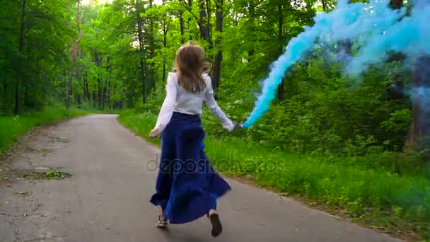 Mulher em roupas bonitas corre pela floresta acenando fumaça colorida, câmera lenta — Vídeo de Stock
