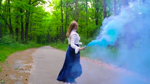 Mujer con ropa hermosa corre por el bosque agitando humo de color, cámara lenta — Vídeo de stock