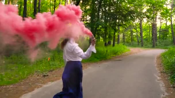 Frau in schönen Kleidern läuft durch den Wald und wedelt mit farbigem Rauch, Zeitlupe — Stockvideo