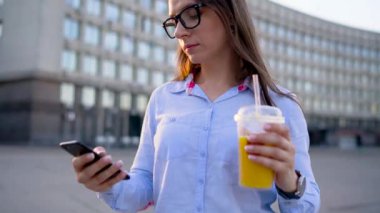 Smartphone üzerinde konuşmak ve sokakta yürürken suyu içme kadın